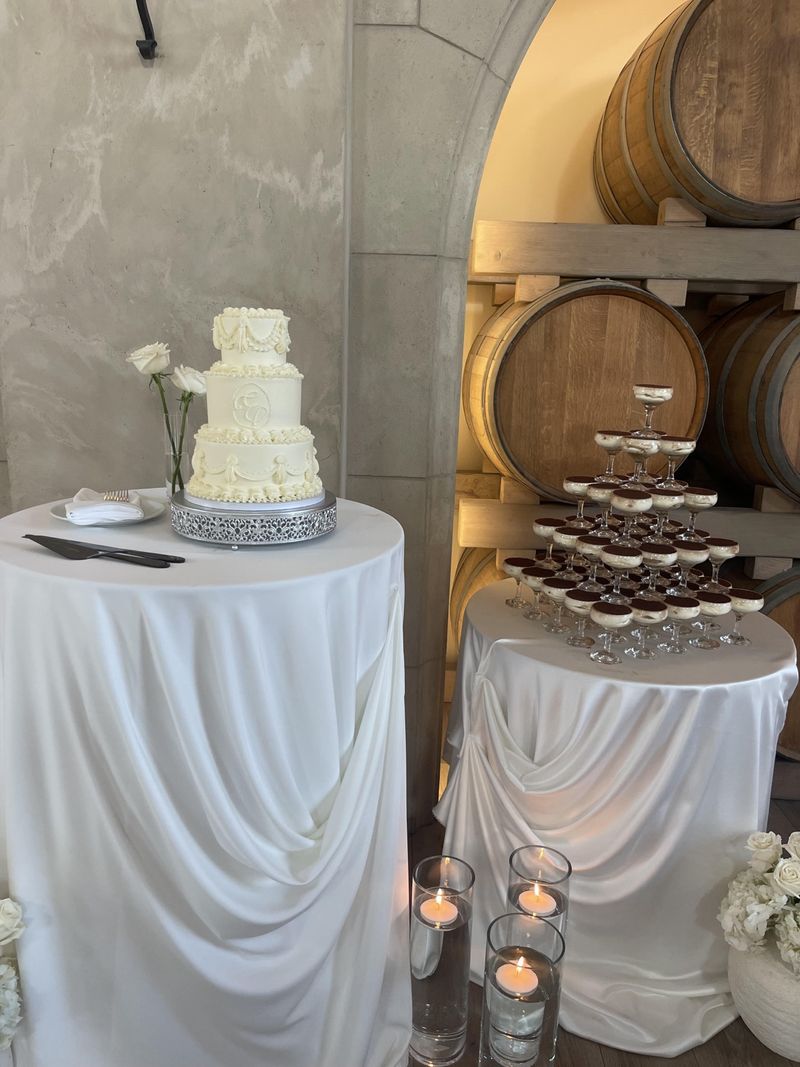 Tiered wedding cake and dessert tower with candlelight beside wine barrels