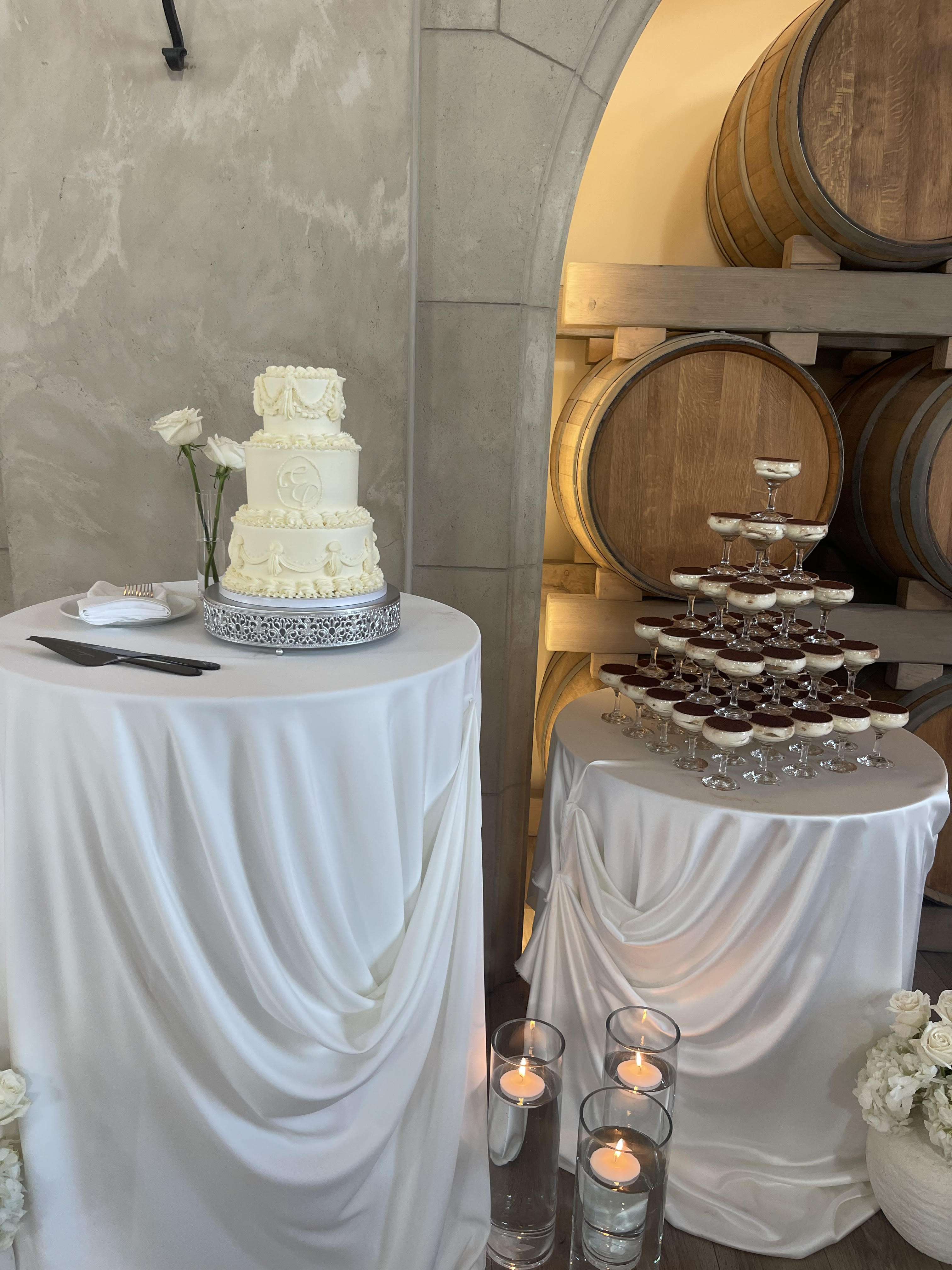 Elegant wedding cake and cupcake tower with candlelight in wine barrel alcove