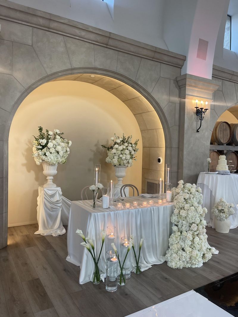 White floral altar arrangement with candles under a stone archway