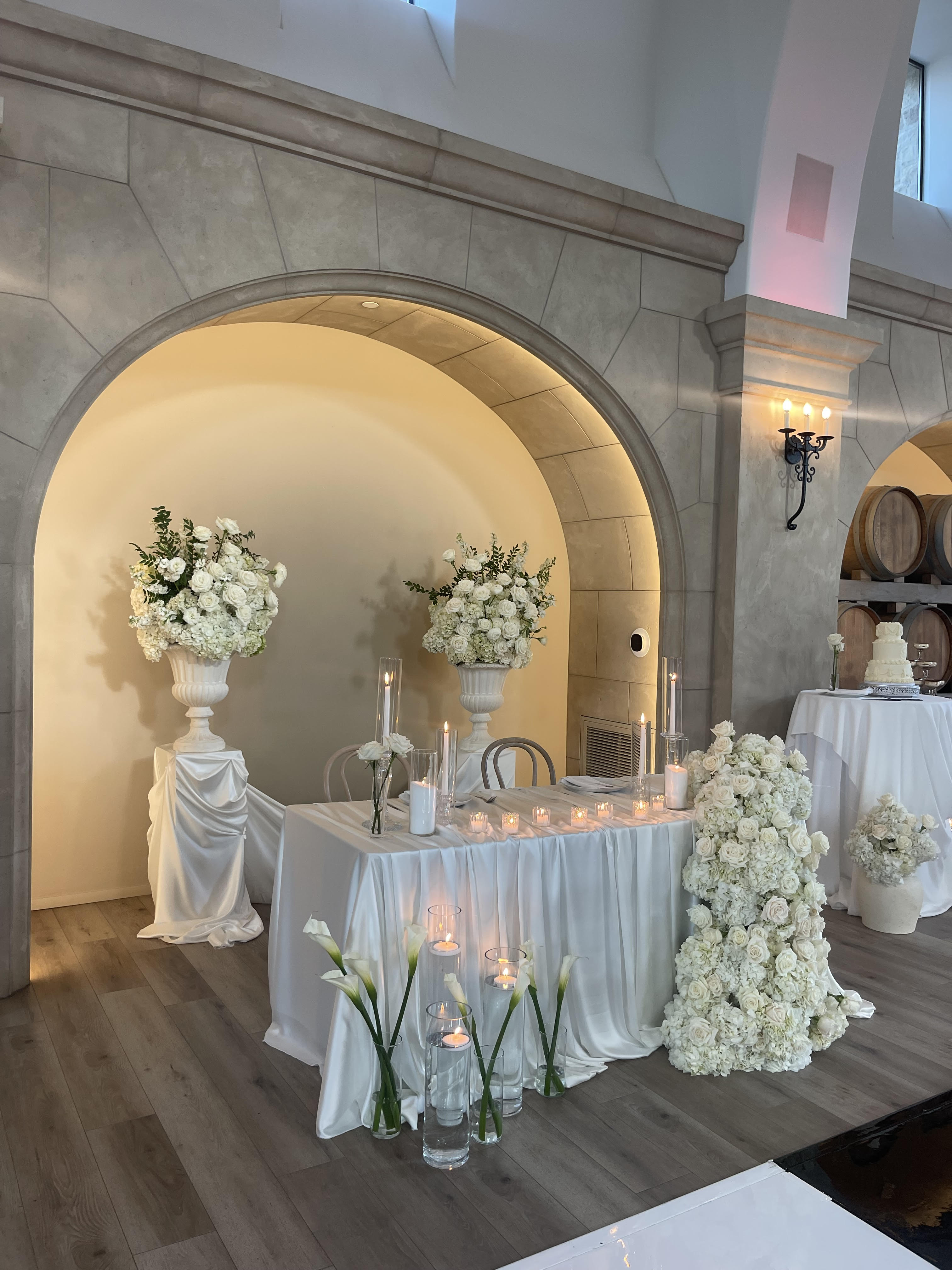 Stunning white floral altar arrangement with candles under stone archway