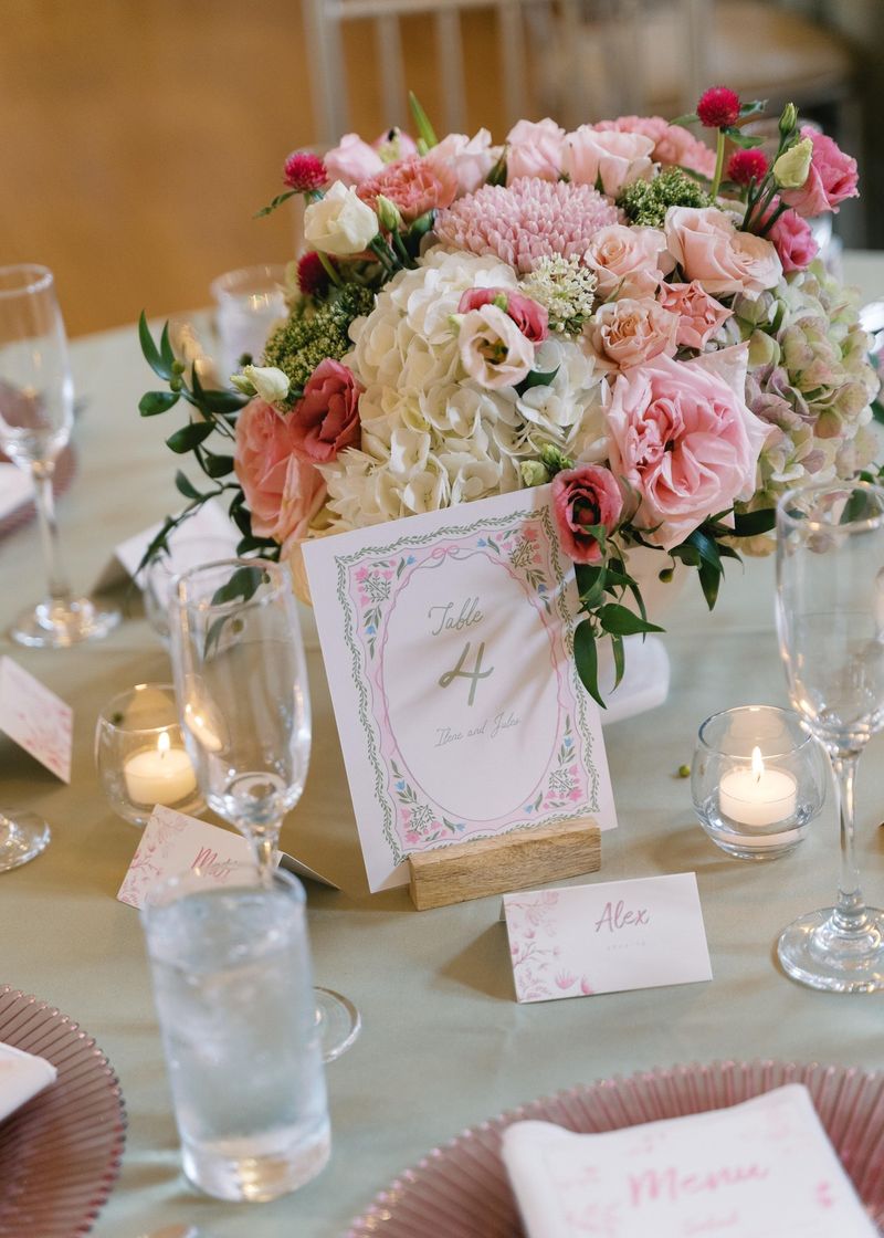 Reception tablescape with pink and blush florals, a table number card and menu cards
