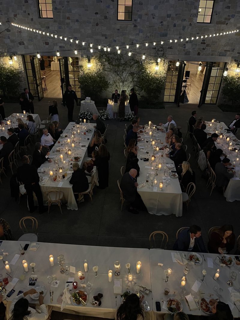 Candlelit outdoor wedding reception under string lights with long guest tables